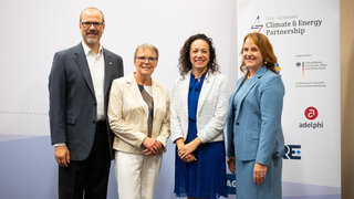Four people standing next to each other, smiling to the camera.