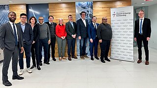 Group picture of people in business attire. On the right is a roll-up with the logo of the US-Germany climate and energy partnership.